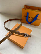 Louis Vuitton monogram belt looped with gold-tone buckle over brown strap