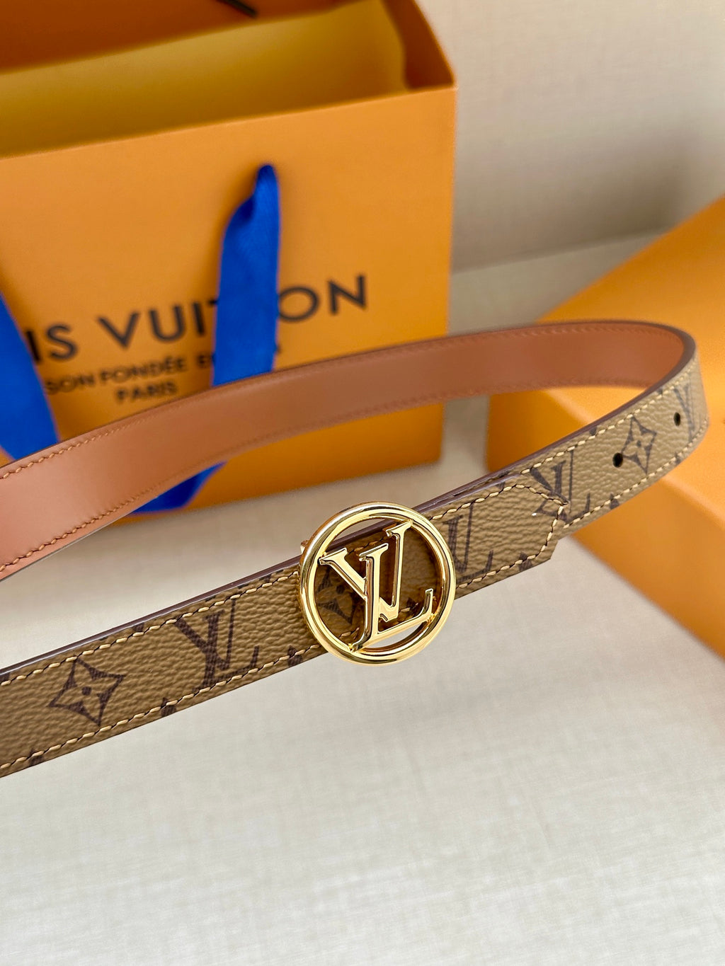 Louis Vuitton monogram belt showing gold buckle and side profile of brown strap