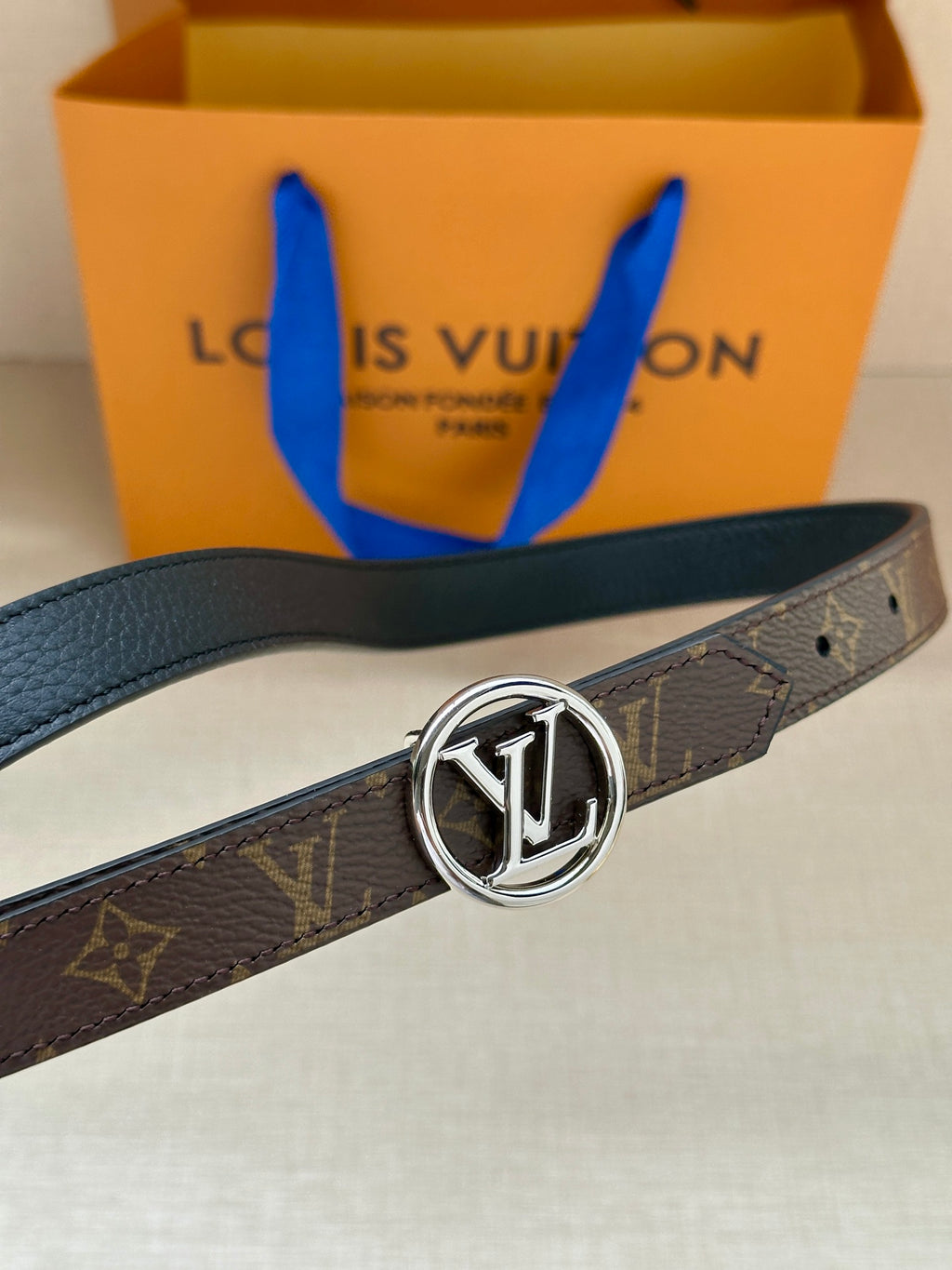 Dark monogram belt with smooth black edge and round silver-tone LV buckle