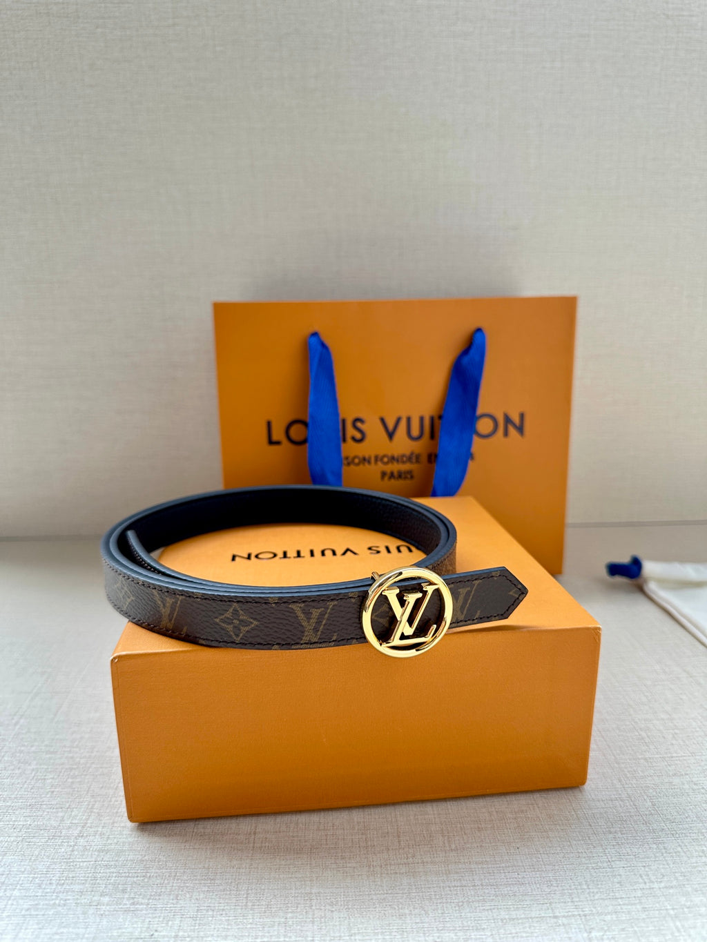 Monogram belt with round silver-tone LV buckle on orange gift box