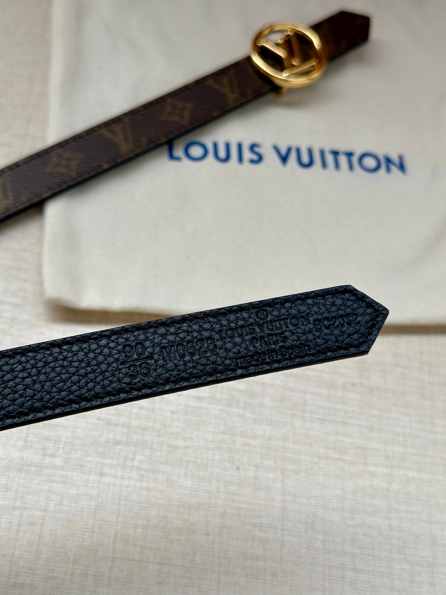 Dark textured leather belt with gold-tone LV buckle and monogram strap end