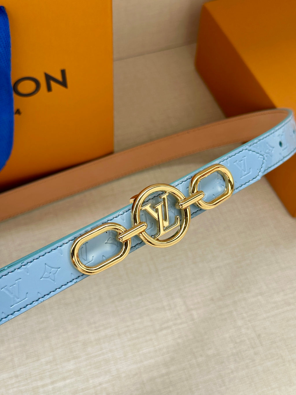 Light blue leather belt with gold LV clasp and double D-ring hardware.