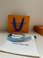 Light blue leather belt with gold LV buckle on a white dust bag.