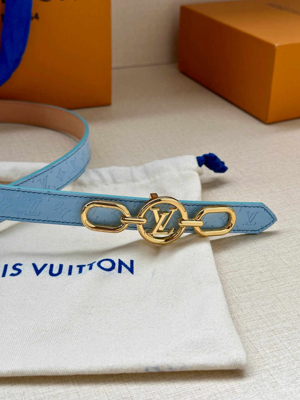 Light blue Louis Vuitton belt with gold double-ring LV buckle detail.