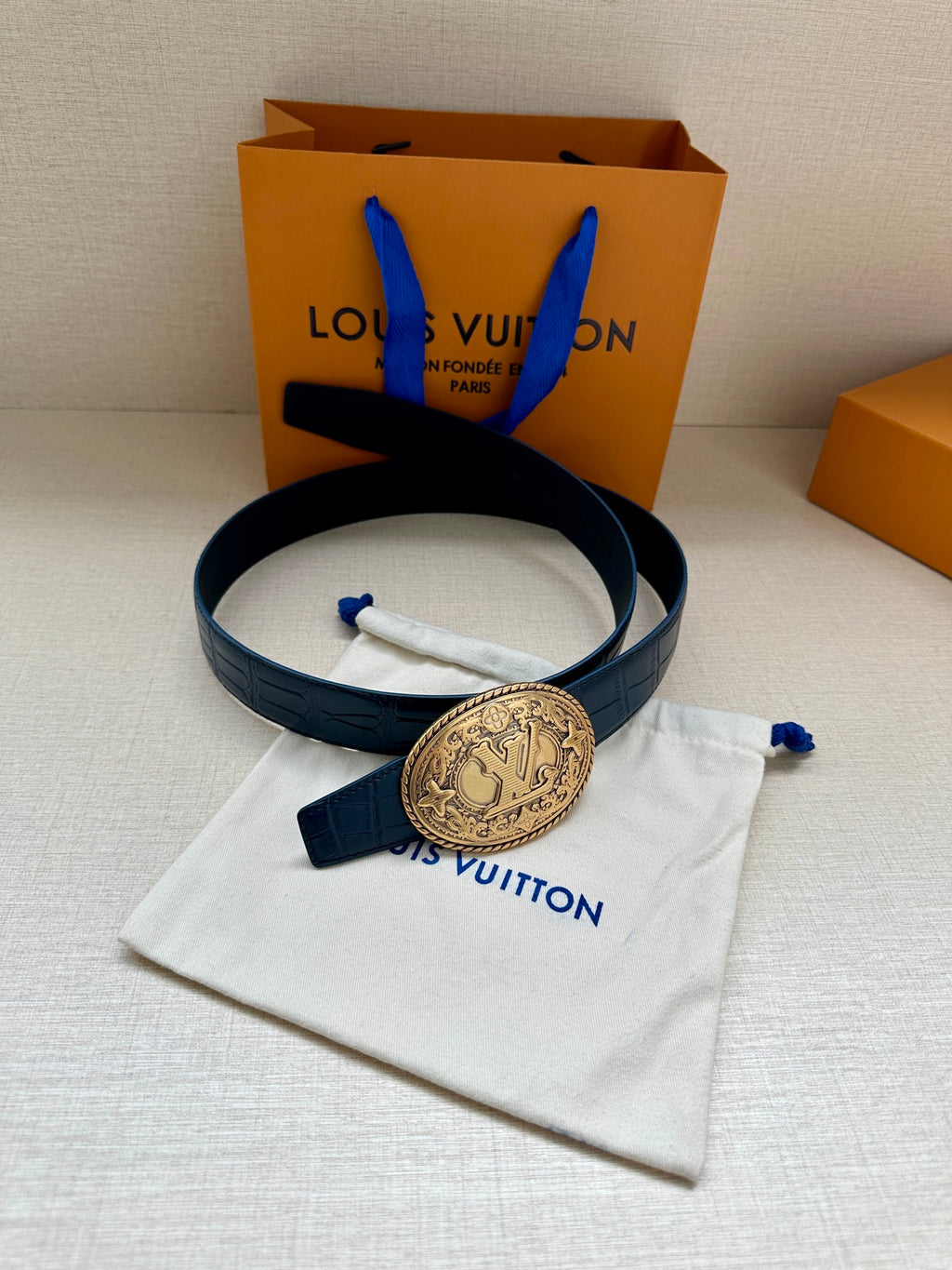 Louis Vuitton dark blue leather belt with gold oval logo buckle, folded