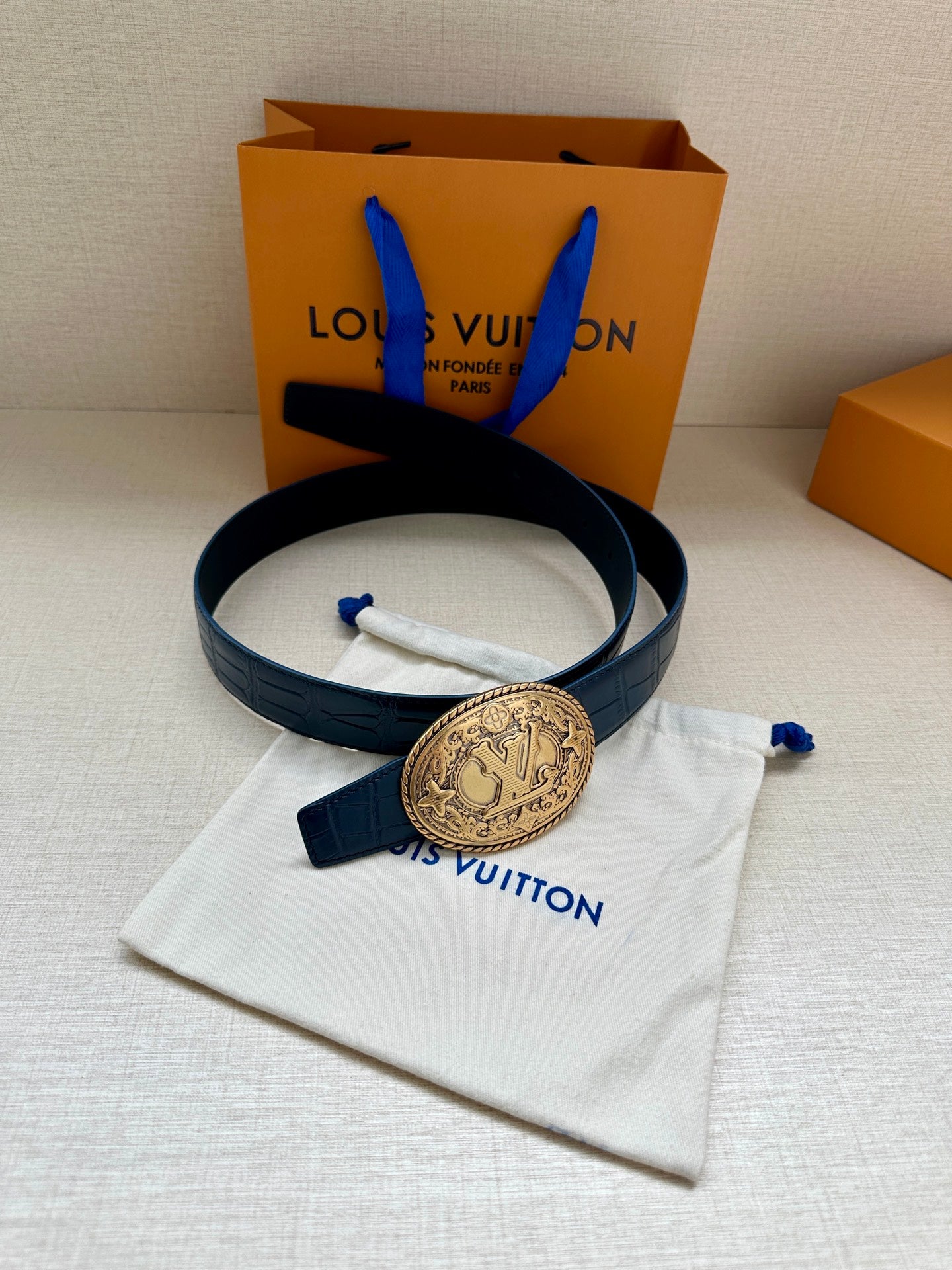 Louis Vuitton dark blue leather belt with gold oval logo buckle, folded