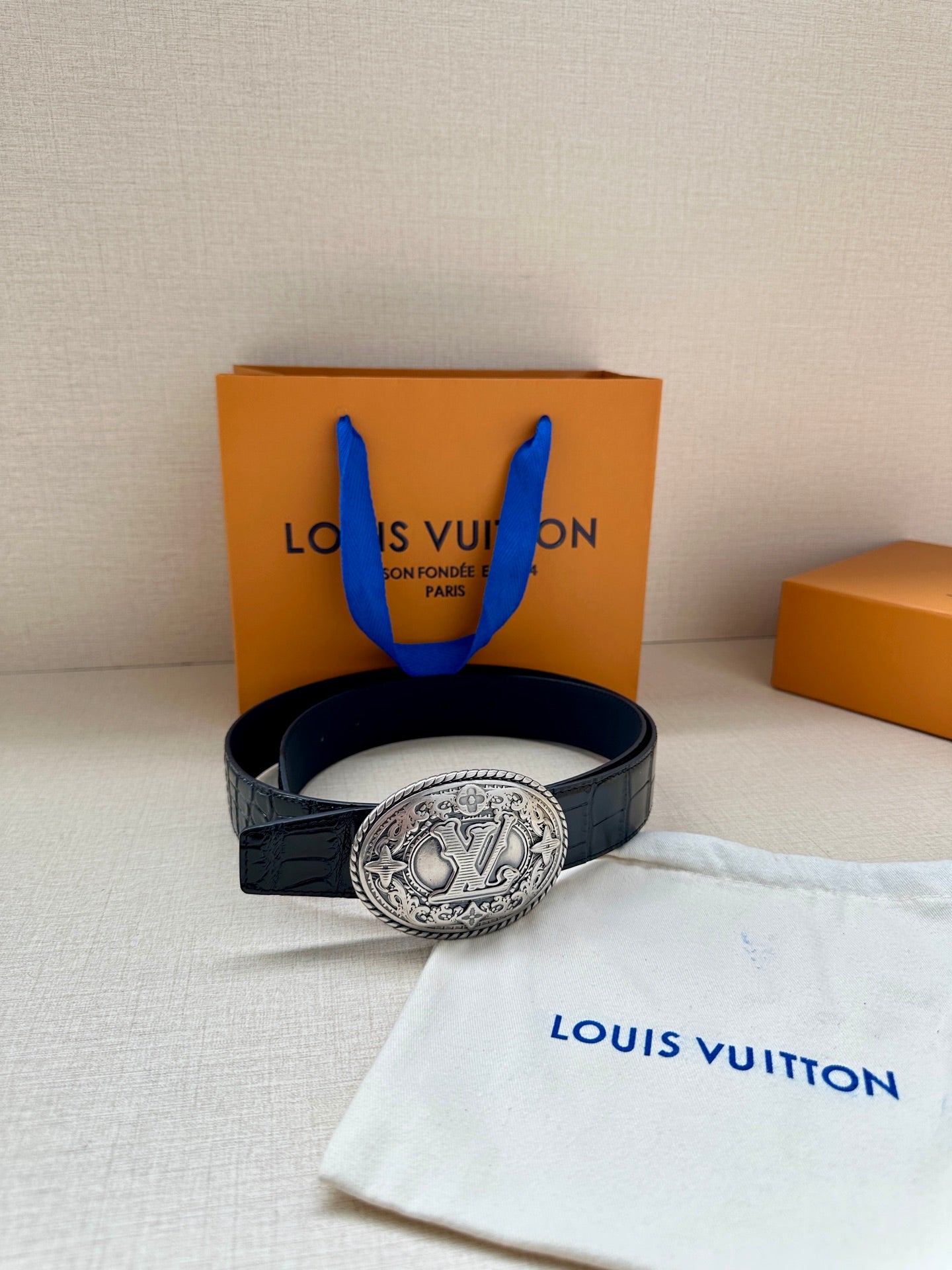 Louis Vuitton belt with dark blue leather and oval silver-tone logo buckle on display