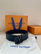 Louis Vuitton leather belt with dark buckle, arranged on white dust bag