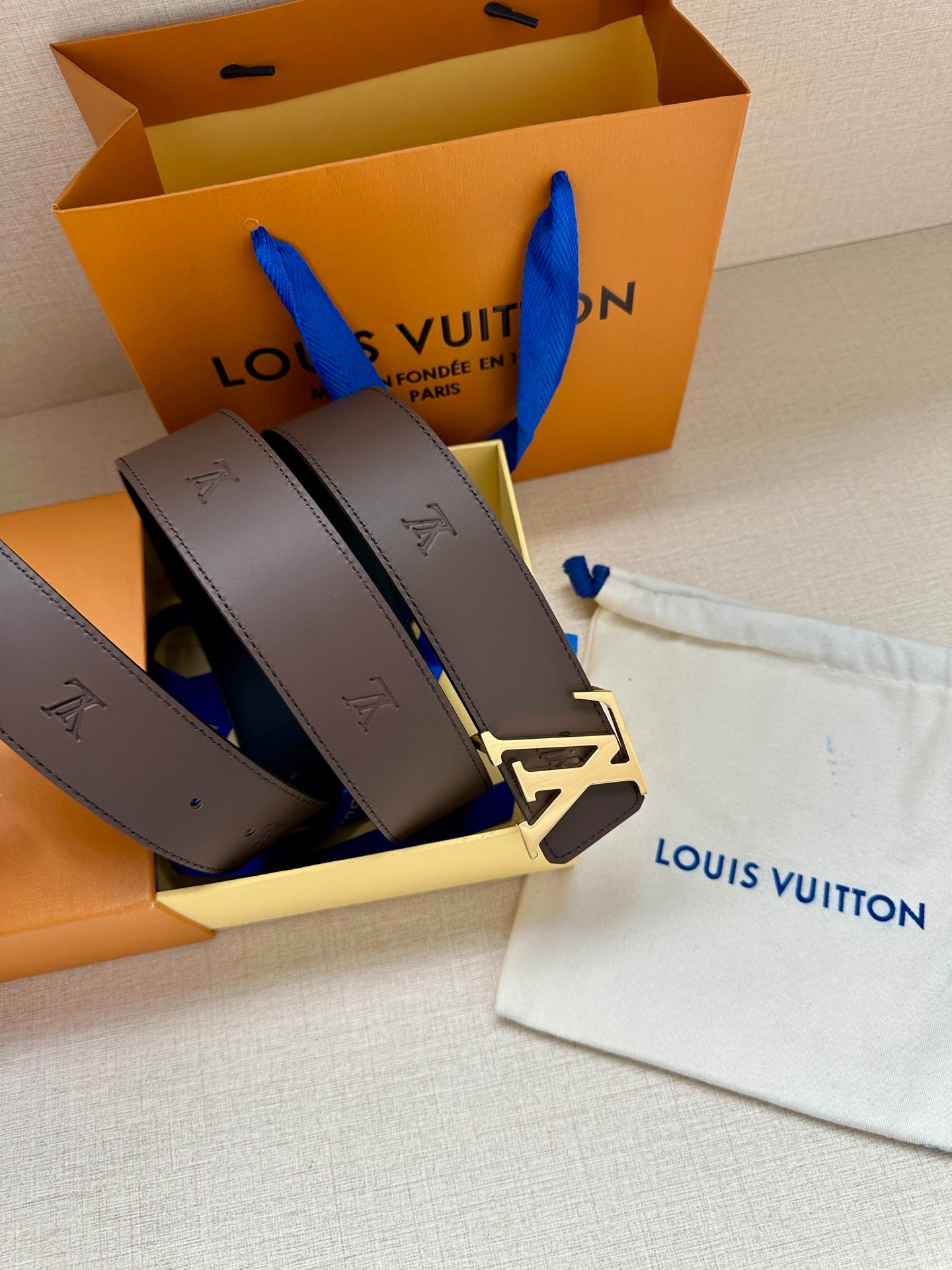 Louis Vuitton belt with dark leather strap, gold LV buckle, and embossed strap