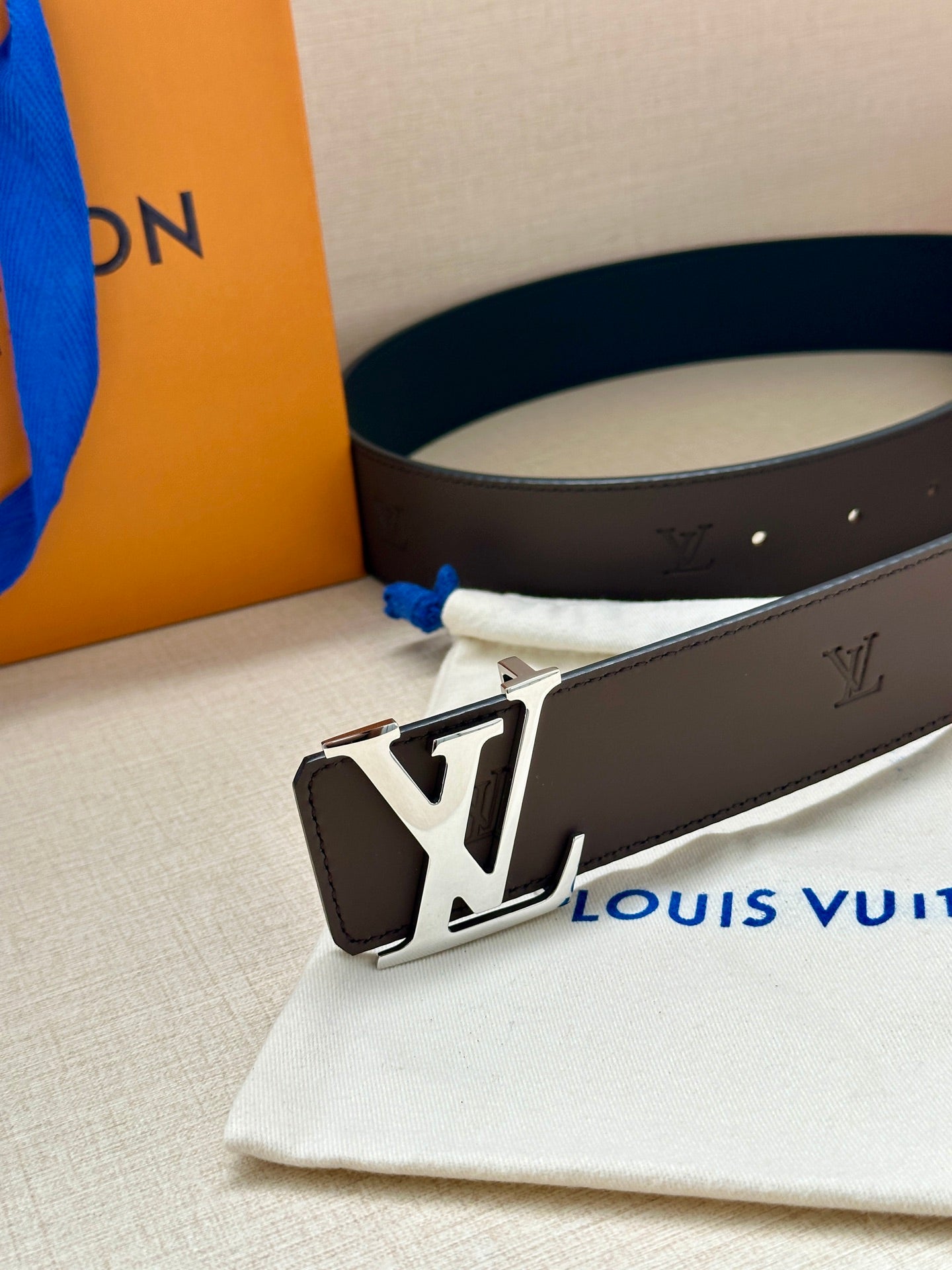 Louis Vuitton belt close-up: dark strap with silver-toned buckle and LV emblem