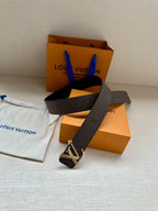 Louis Vuitton belt with dark leather strap and gold LV buckle, angled view