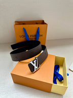 Louis Vuitton belt with dark strap and gold LV buckle, resting on a box