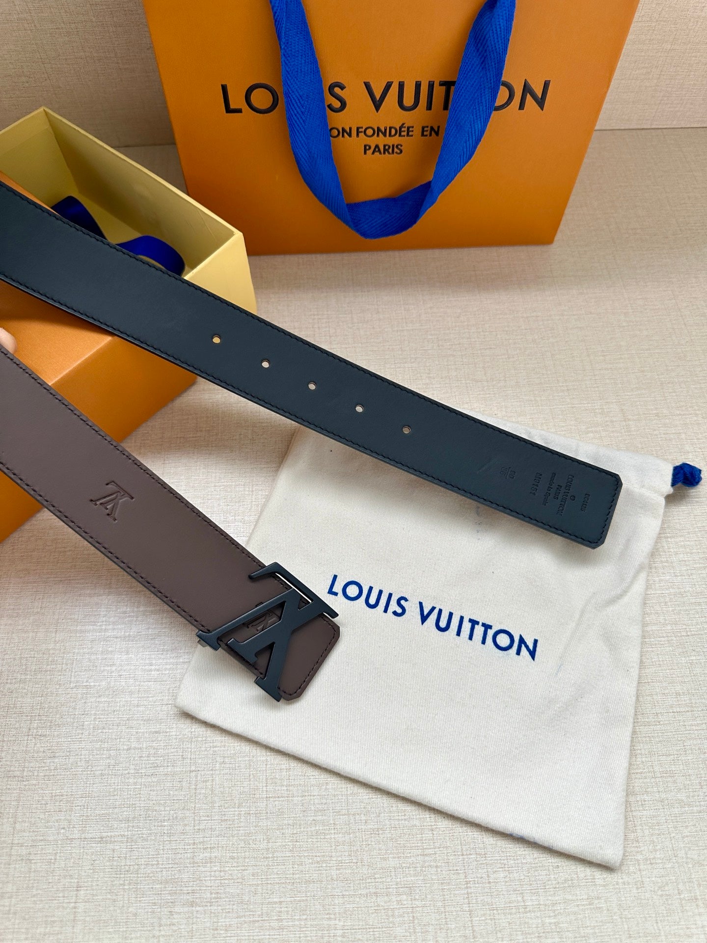 Louis Vuitton belt laid flat: dark brown strap with metal buckle and logo studs