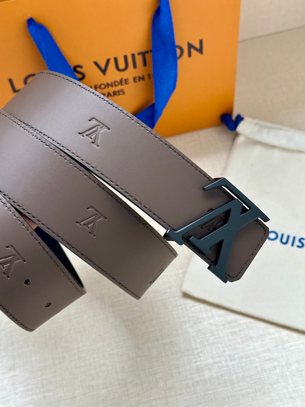 Louis Vuitton belt detail: dark brown strap with LV buckle and engraved emblems