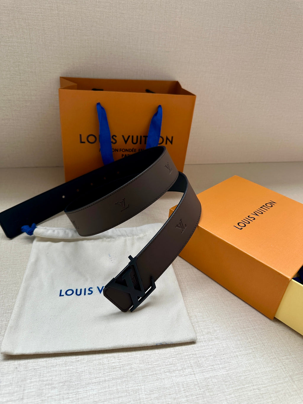 Louis Vuitton belt with dark brown strap and black LV buckle on dust bag