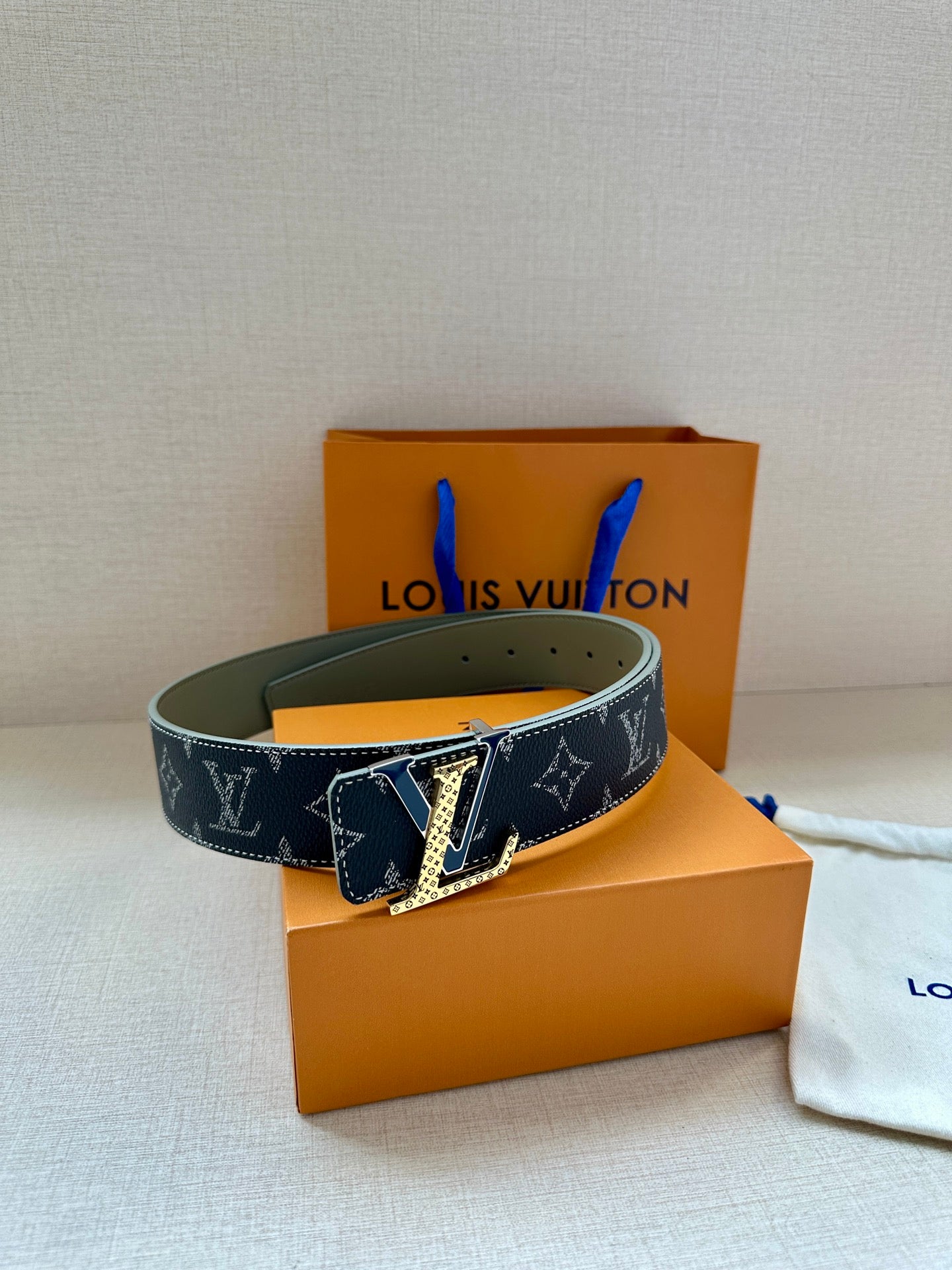 Monogram belt with dark canvas strap and gold-tone buckle on olive leather lining