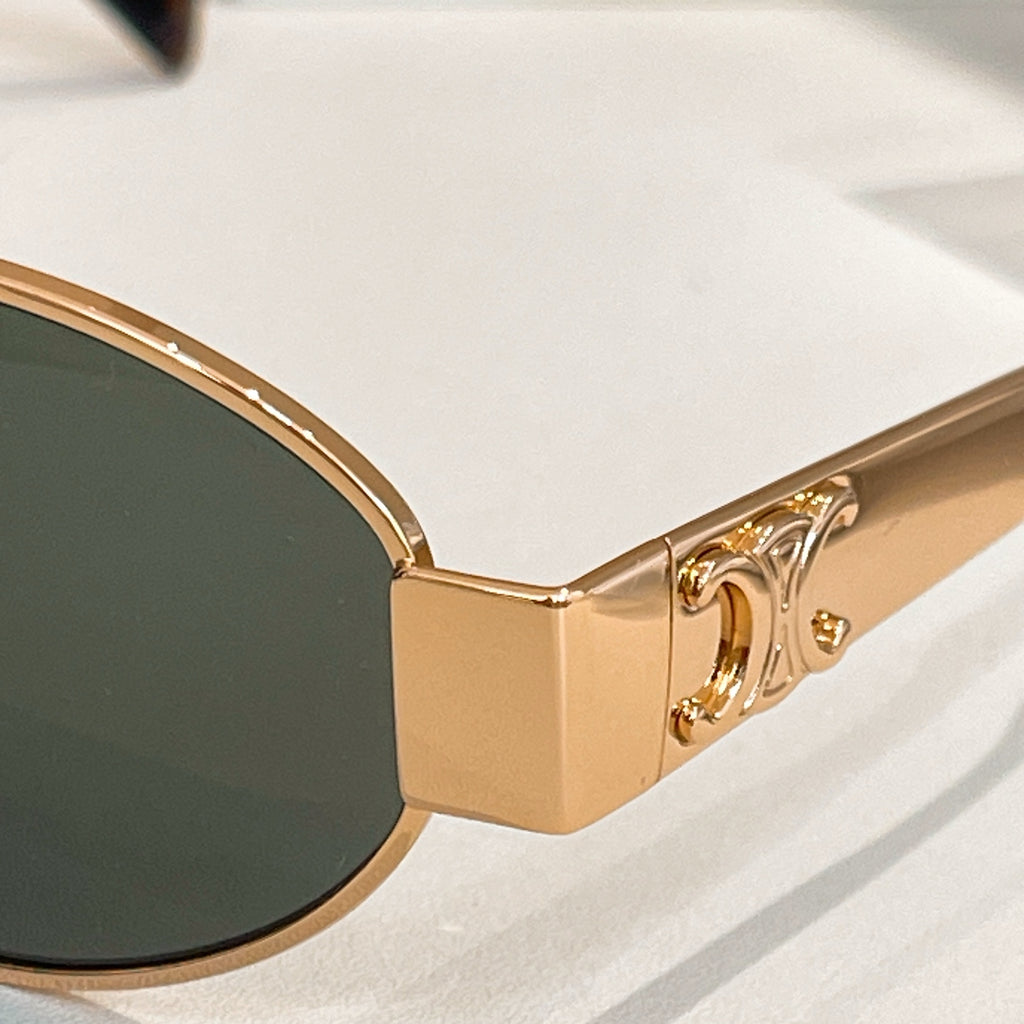 Gold-tone cat-eye sunglasses with dark lenses and curved front corners