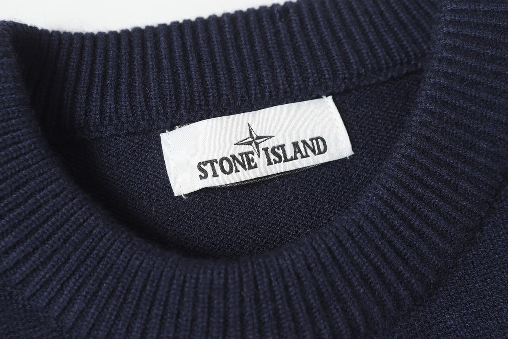 Stone Island logo label at the neck of a dark navy knit sweater.