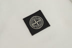 Black Stone Island logo patch on white polo shirt fabric