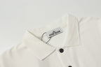 White polo shirt with folded collar and hanging Stone Island label