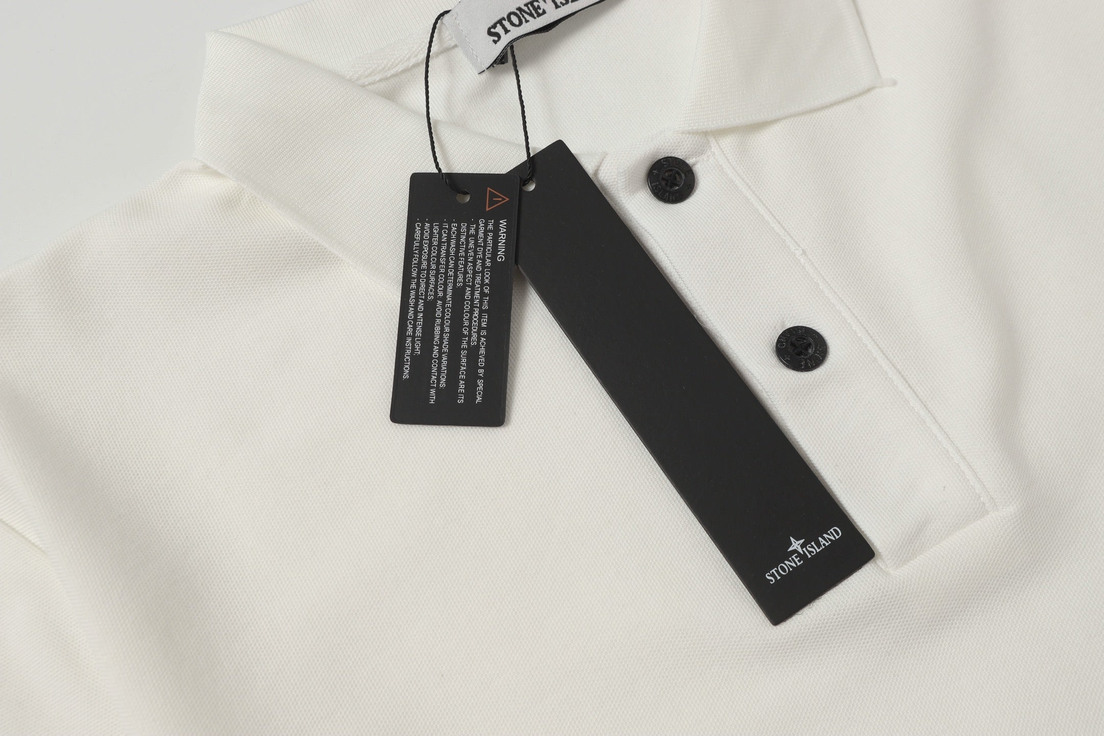White polo shirt collar with black button and hanging size tag