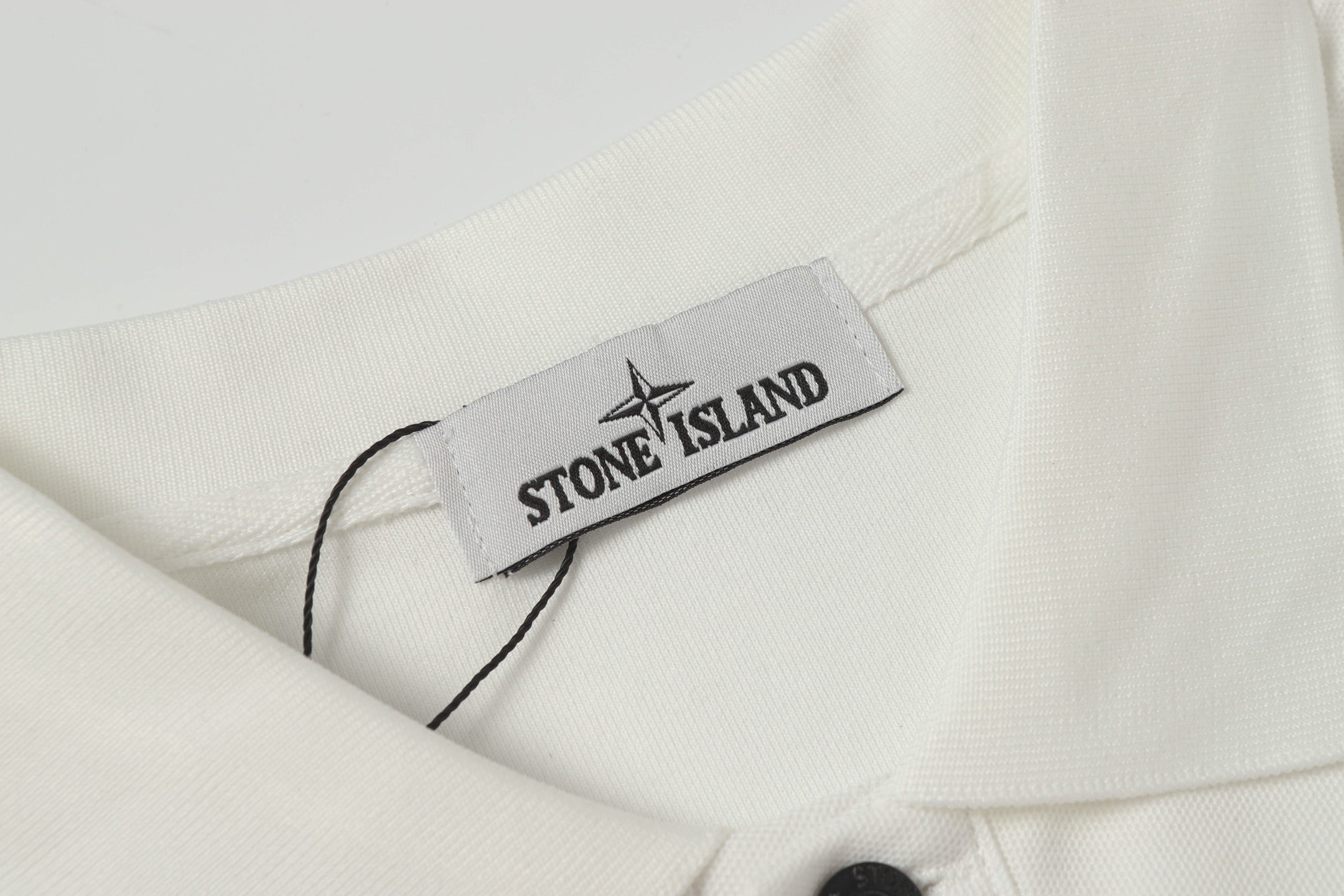 Stone Island label on white polo shirt neckline with dark button