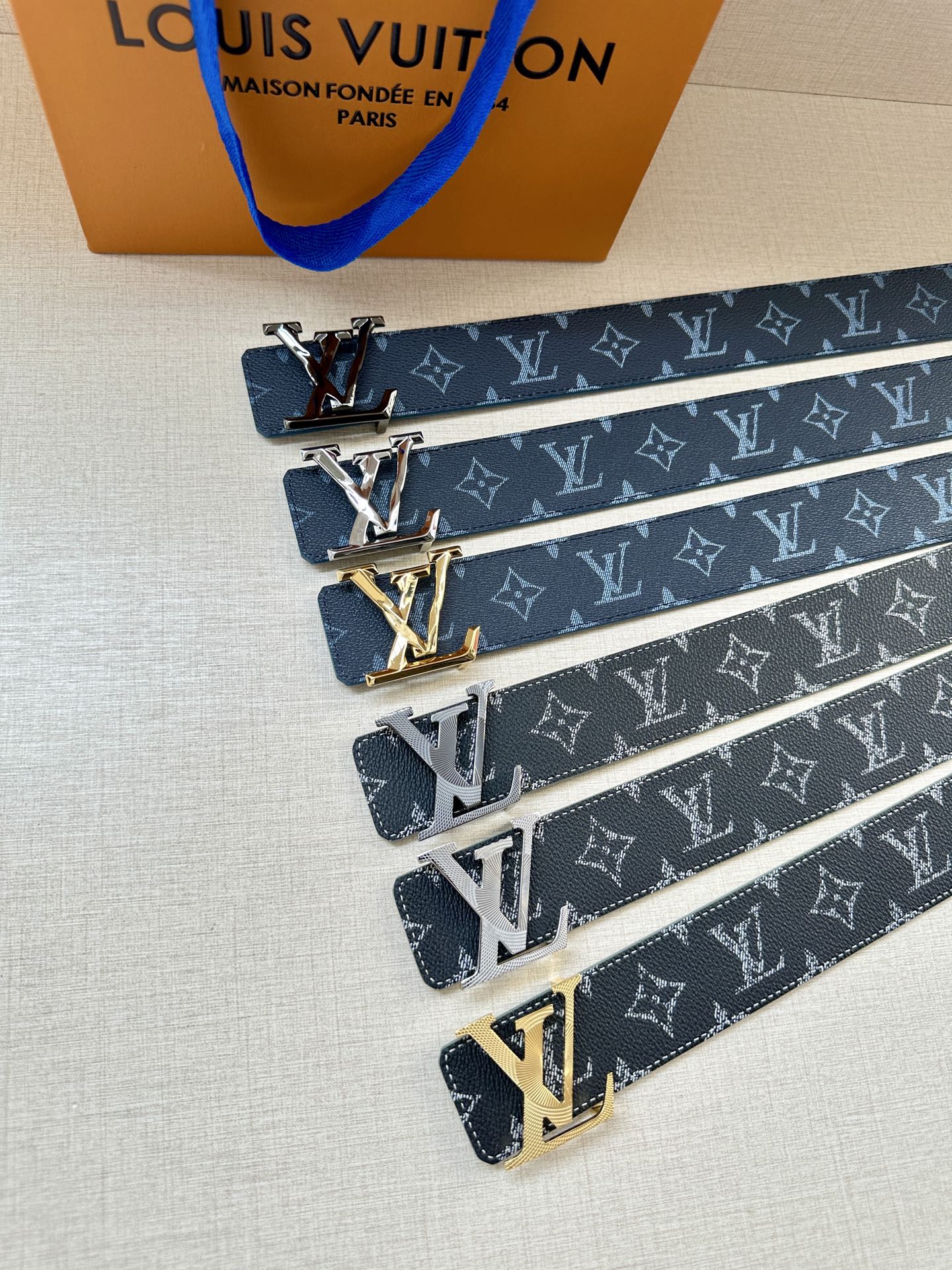 Louis Vuitton monogram belt set showing dark blue straps and gold-toned LV buckles