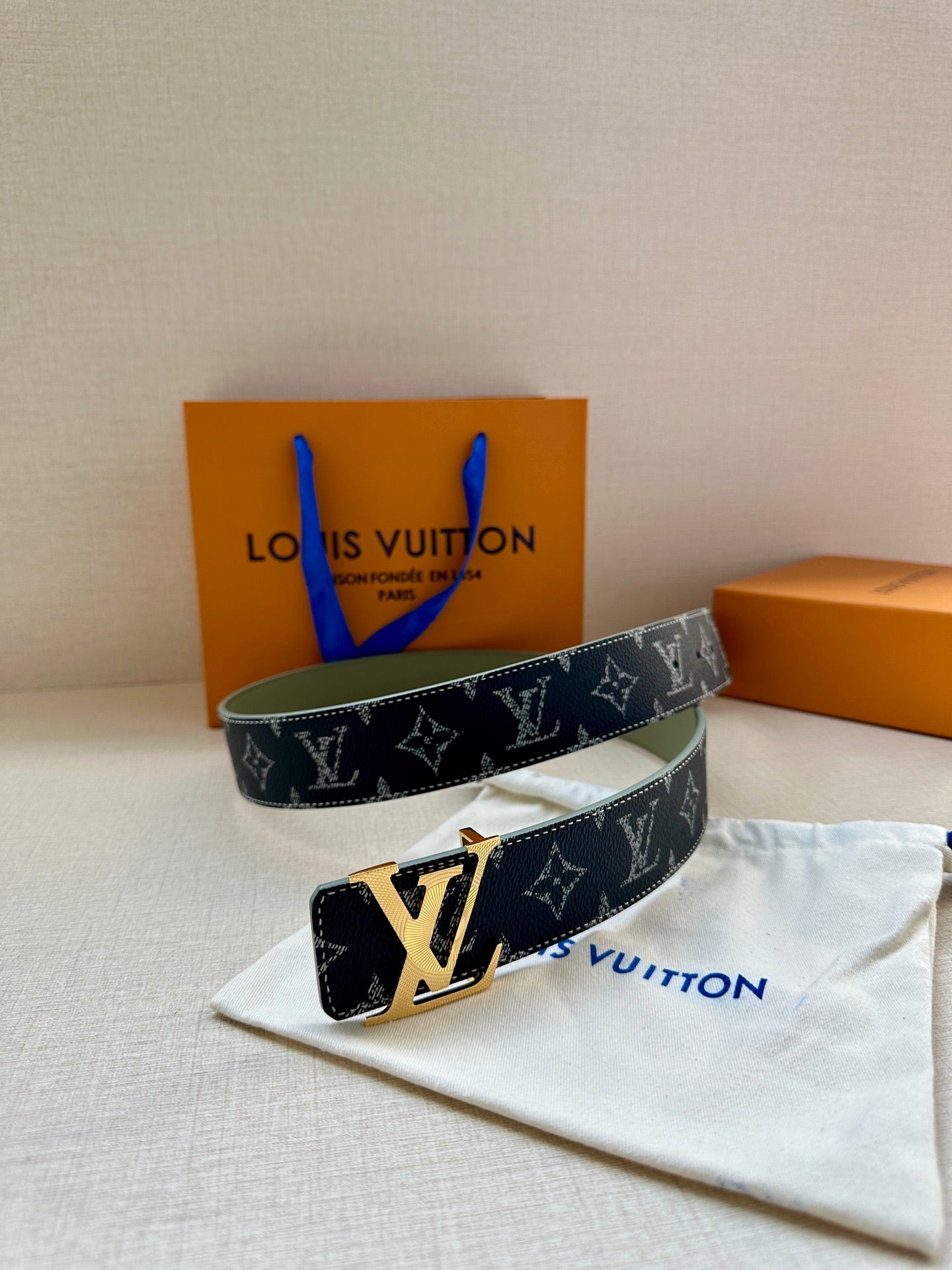 Two-view Louis Vuitton monogram belt with silver buckle, folded on cloth