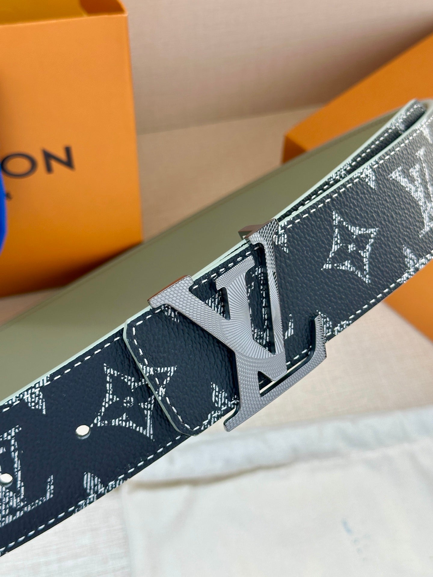 Louis Vuitton monogram belt detail with engraved buckle and dark leather edge