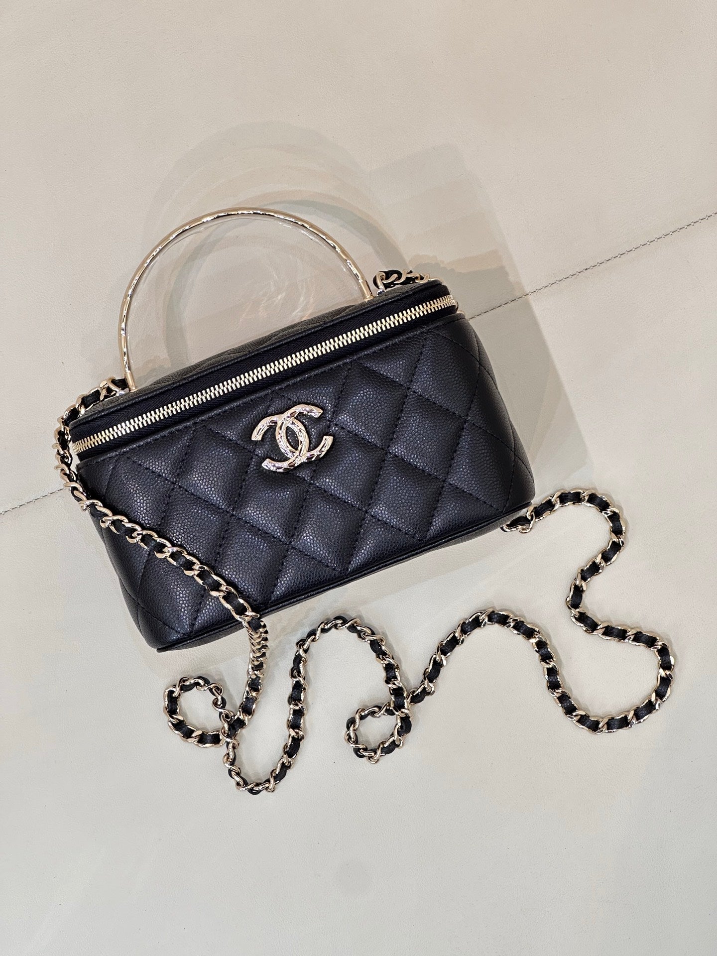Dark navy quilted mini bag with top handle, front CC logo, and silver-tone chain strap.