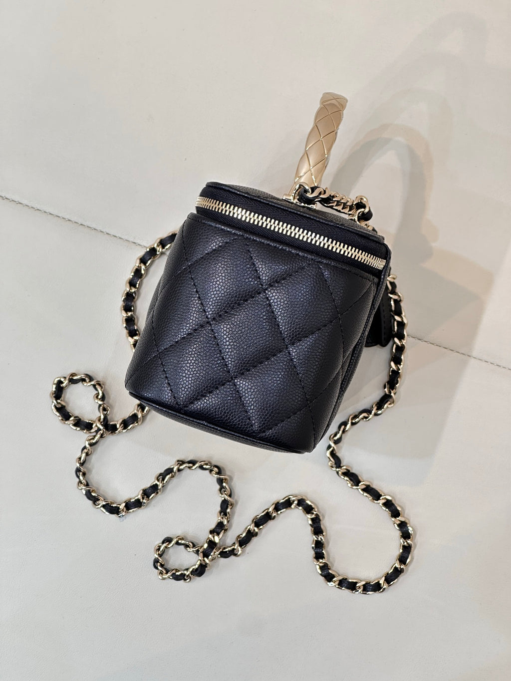 Dark navy quilted mini bag with top zip, chain crossbody strap, and gold-tone hardware.
