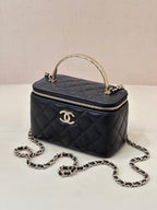 Dark navy quilted mini bag with top handle, front CC logo, and chain strap with loops.