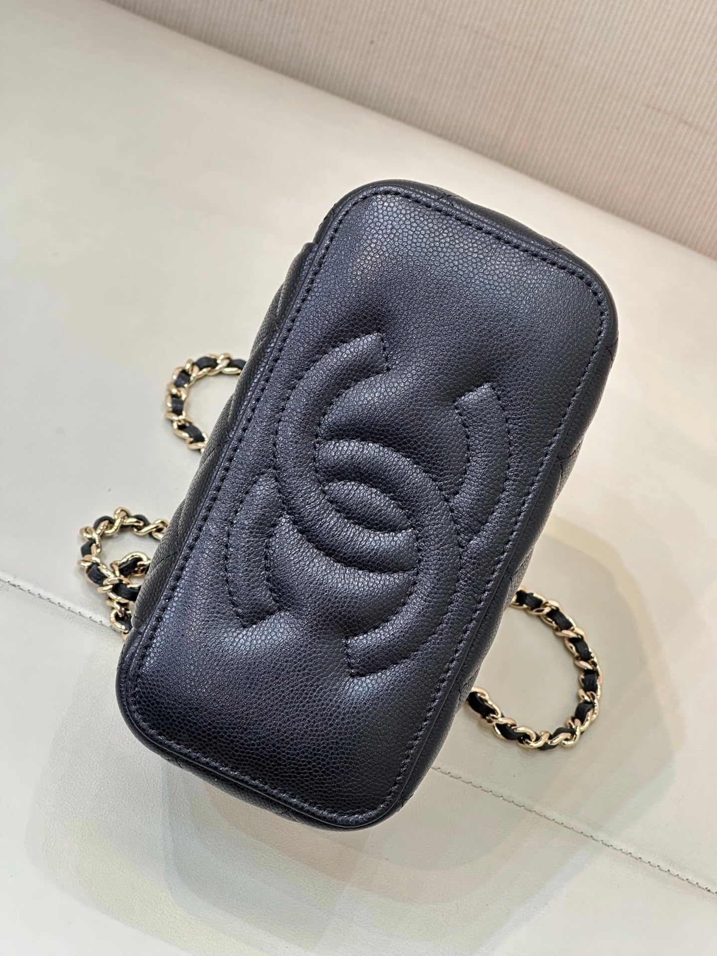 Dark navy quilted phone-case style pouch with embossed CC logo and chain strap.
