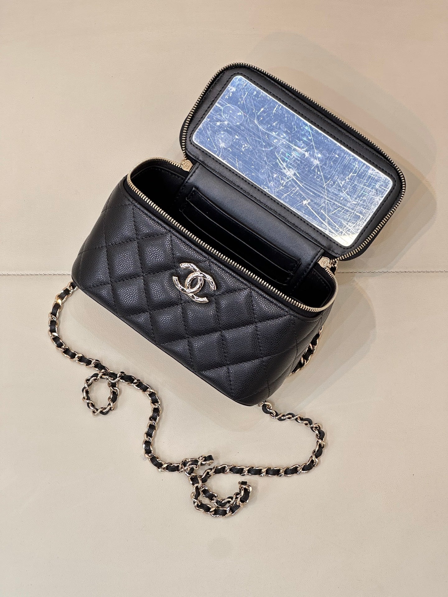 Dark navy quilted mini bag with zip-top pouch and CC logo; small chain strap attached.