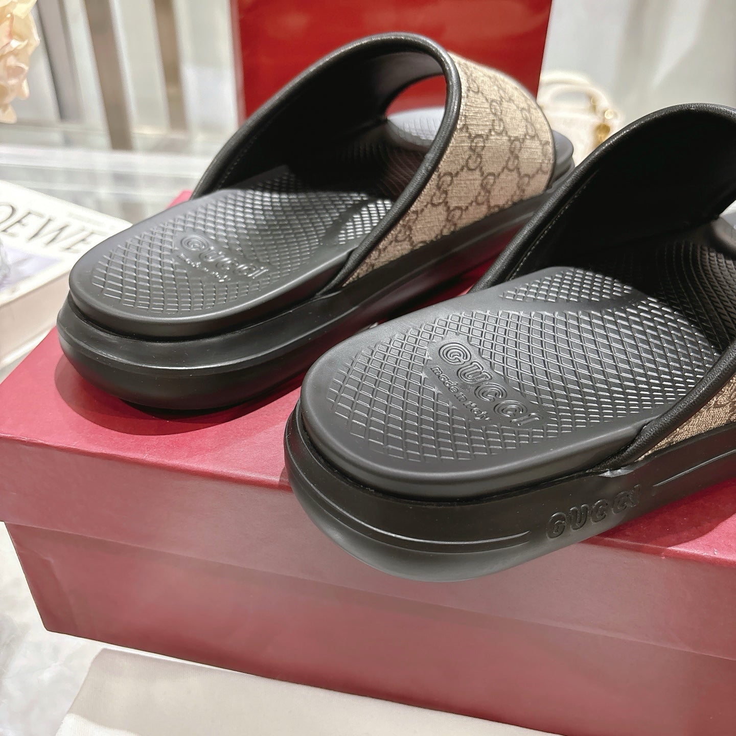 Gucci slide sandals close-up; black textured footbeds with tan GG canvas straps
