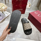 Gucci slide sandals close-up; black outsole with geometric tread, tan GG slide upper
