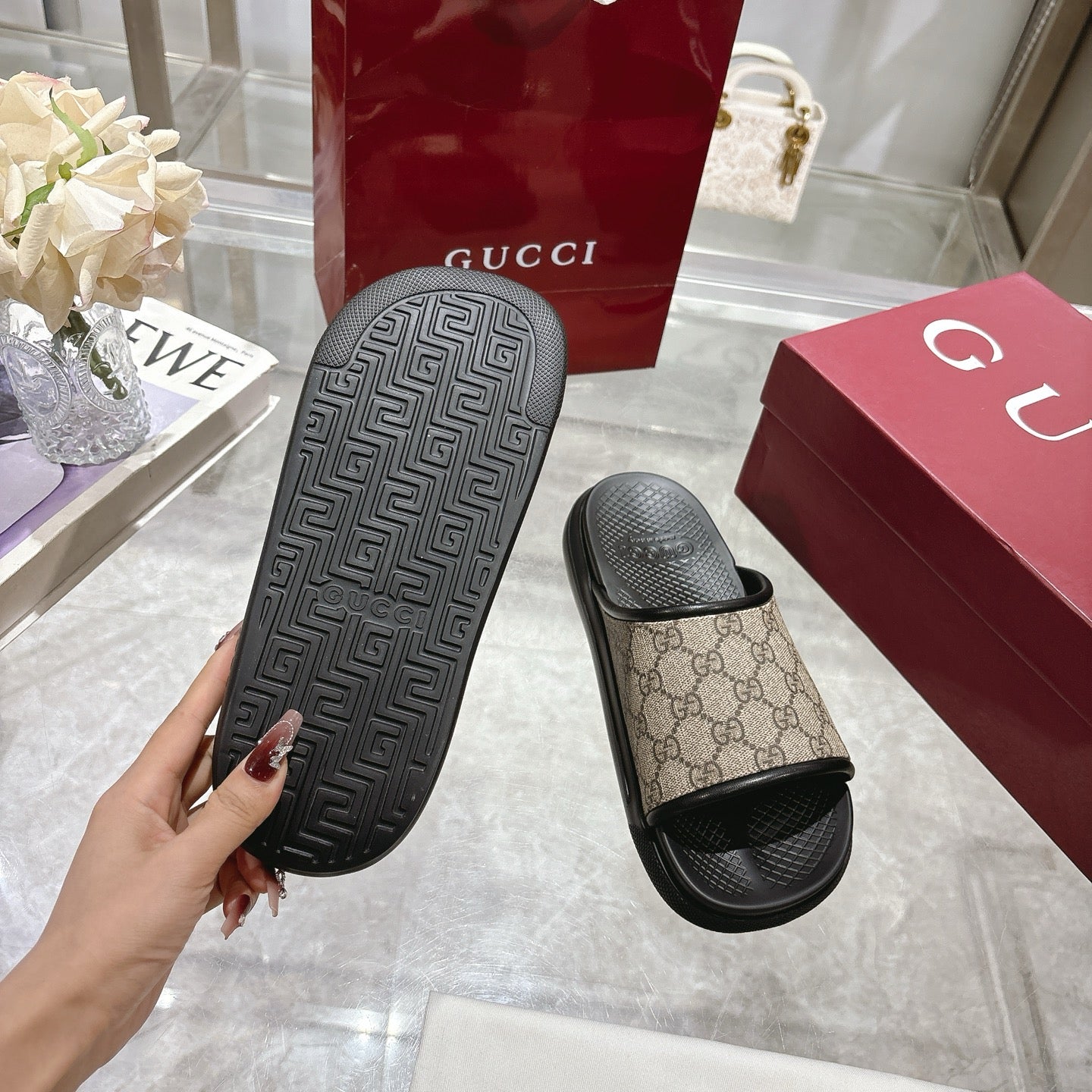 Gucci slide sandals close-up; black outsole with geometric tread, tan GG slide upper