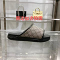 Gucci slide sandals with dark rubber sole and GG canvas upper, black strap detail