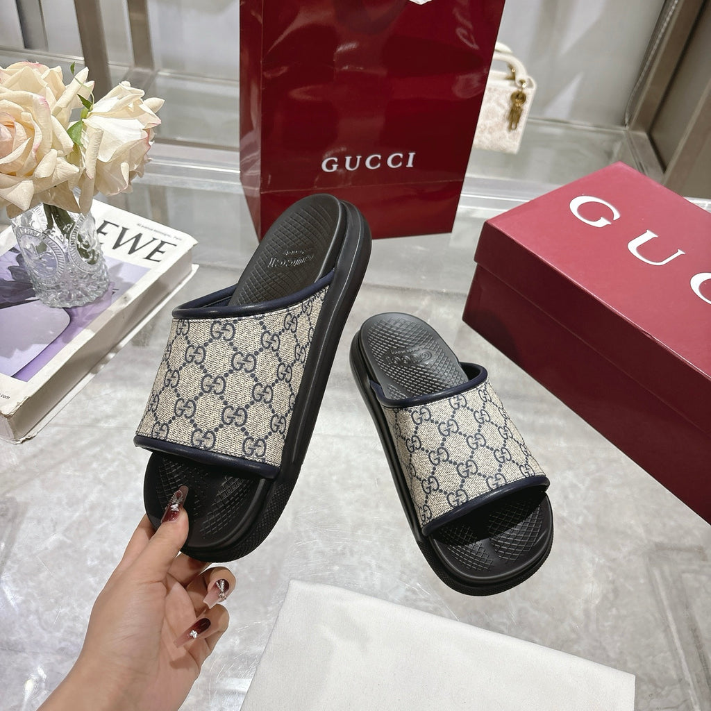 Gucci GG slide sandals, held in hand, featuring black footbed and canvas strap