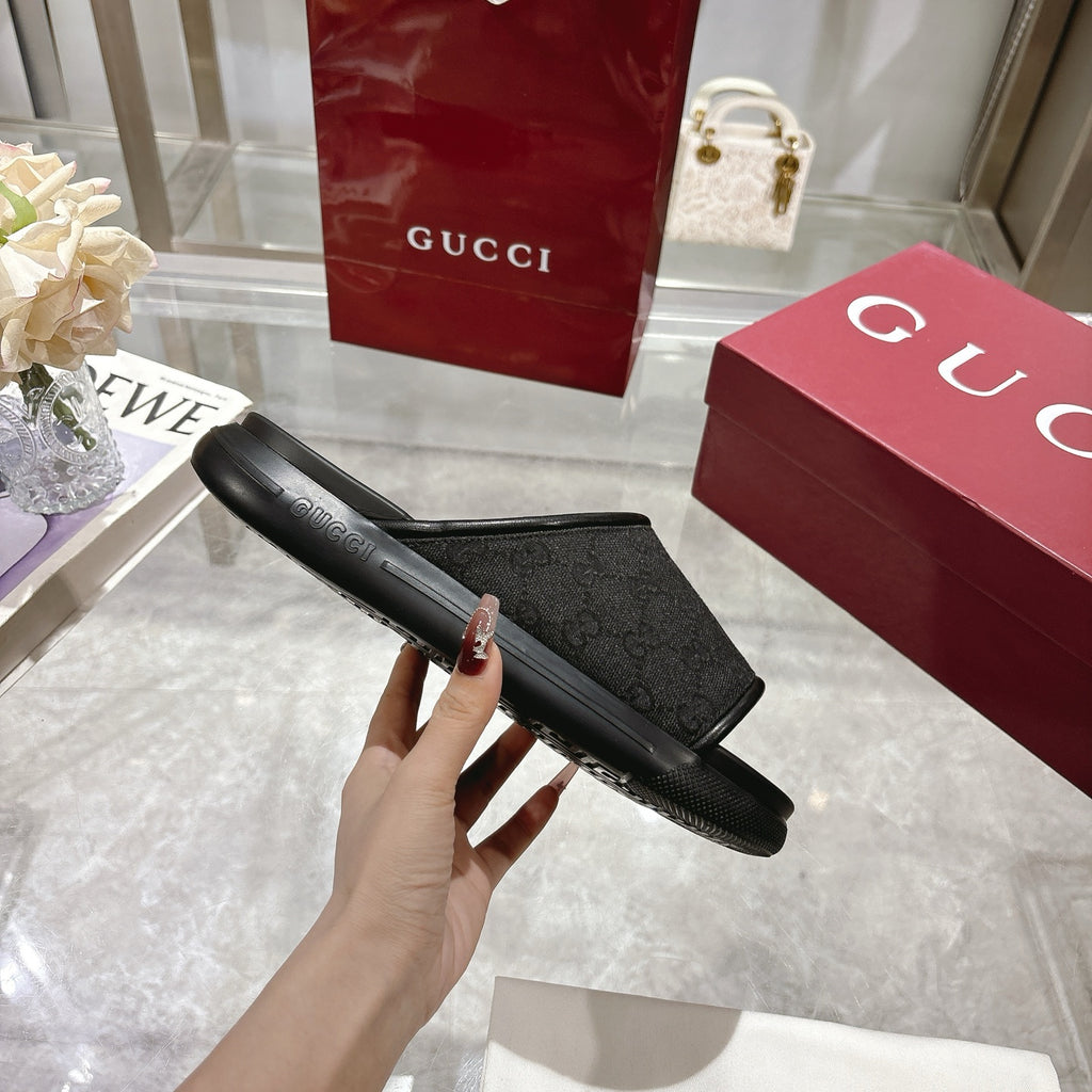 Gucci black slide sandals shown from side, textured strap and contoured sole