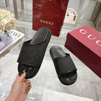 Gucci black slide sandals with monogram strap; shopper holds one sandal by heel