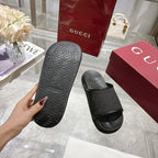Gucci black slide sandals showing tread outsole on one footbed