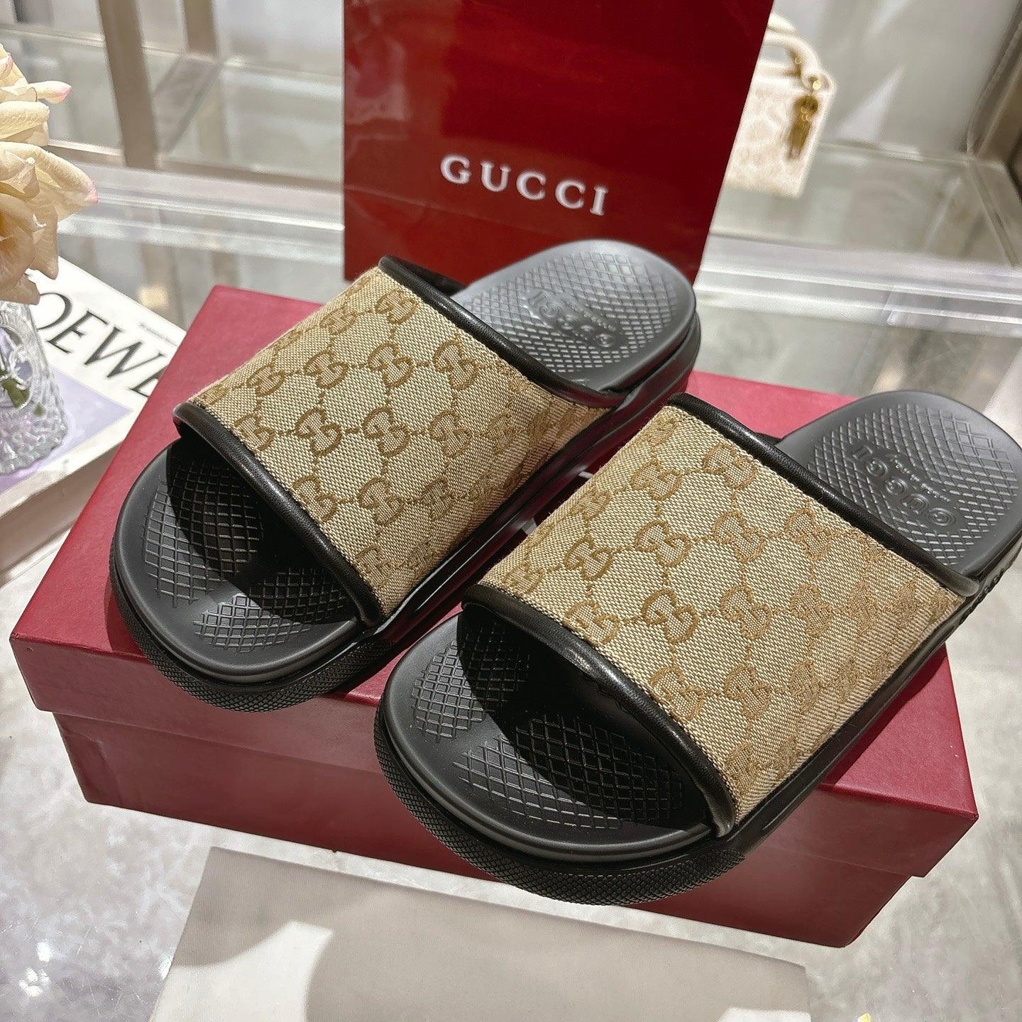 Gucci slide sandals on box: beige GG canvas straps and black textured slide soles
