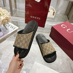 Gucci slide sandals held in hand: beige GG canvas strap with black rubber sole
