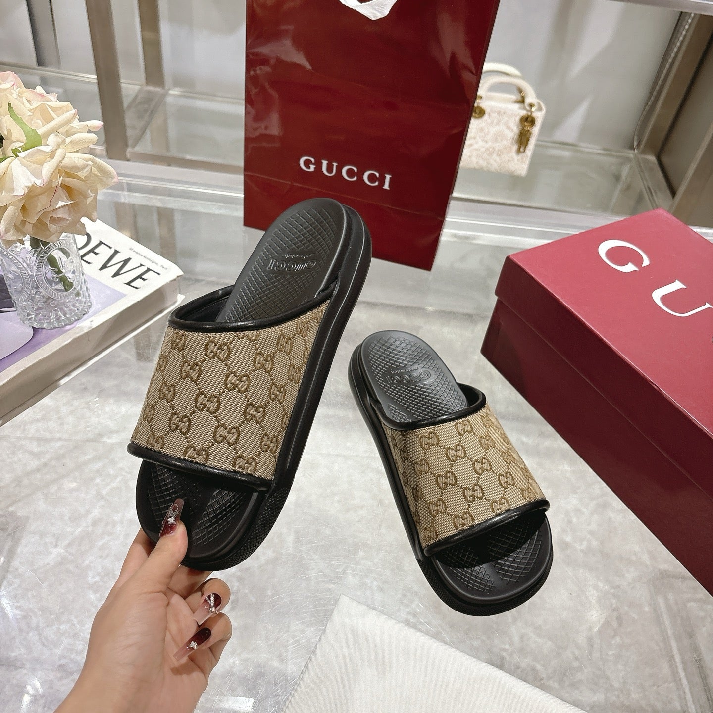 Gucci slide sandals held in hand: beige GG canvas strap with black rubber sole