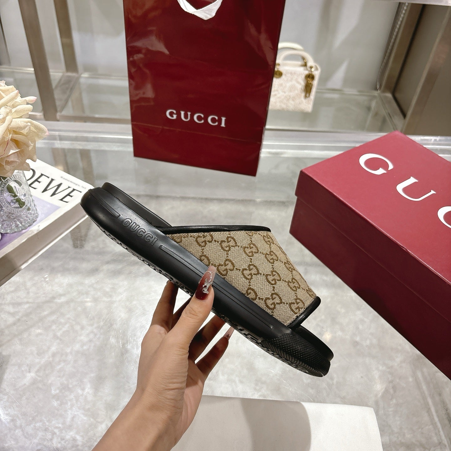 Gucci slide sandals side view: beige GG canvas strap on black rubber footbed