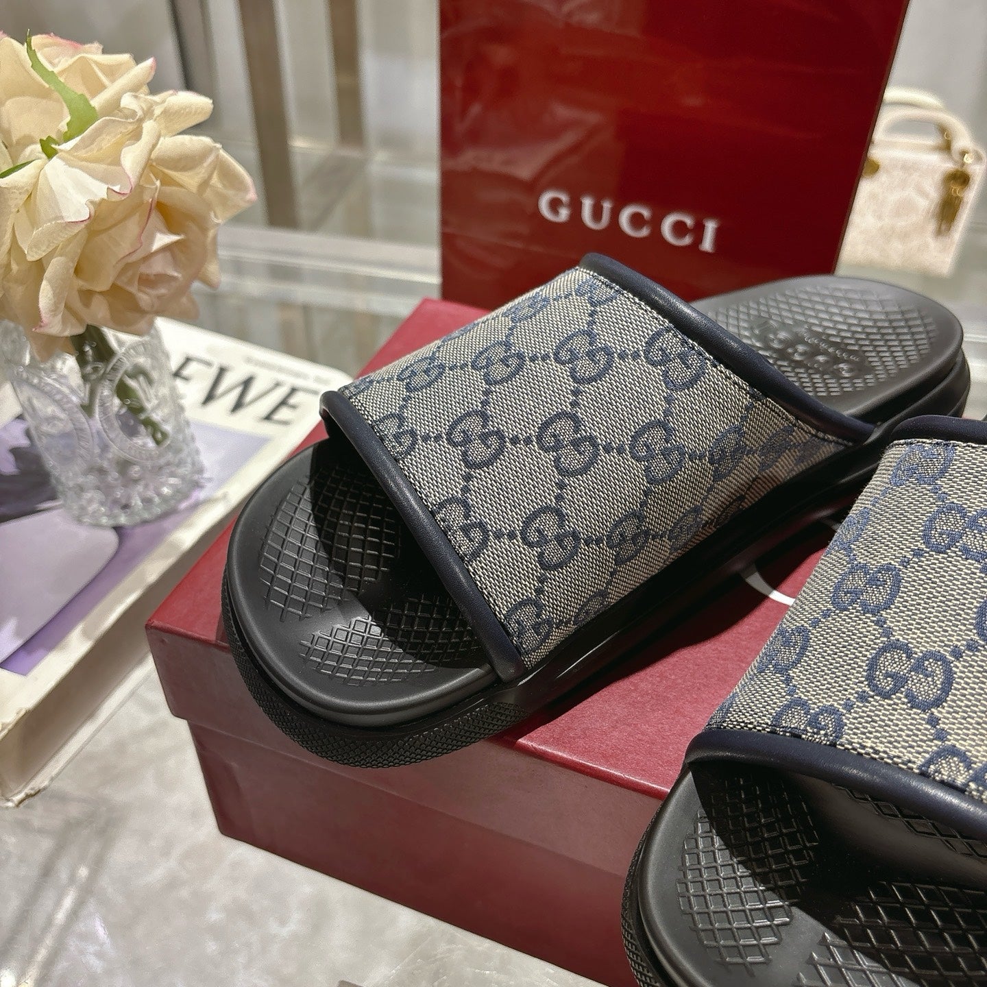 Gucci slide sandals close-up, GG monogram strap over black footbed