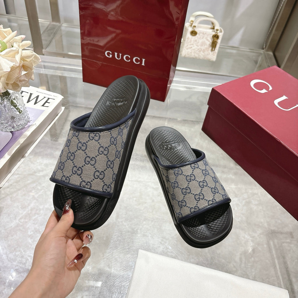 Gucci slide sandals with GG monogram strap and black rubber sole, held up