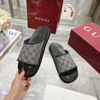 Gucci slide sandals with GG monogram strap and black rubber sole, held up