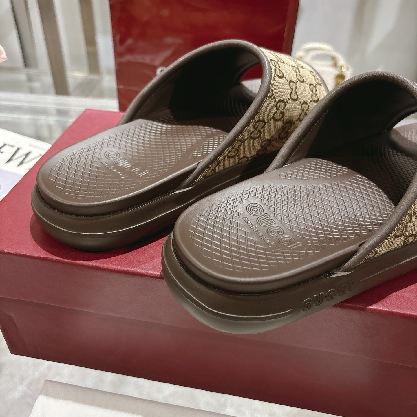 Gucci GG slide sandals close-up, tan monogram straps with dark lining